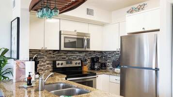 A modern kitchen with stainless steel appliances, a granite countertop, and a backsplash with a mosaic tile pattern.