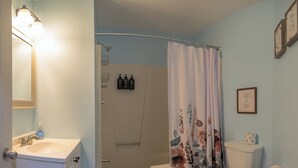 A bathroom with a shower, toilet, sink, and a framed quote on the wall. - Beautiful Apartments in Thorsen Road Maine (Hancock)