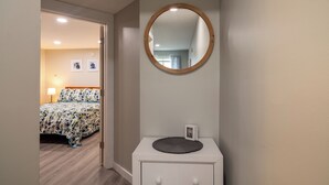 A bedroom with a bed, a bedside table with a mirror, and a door leading to another room. - Beautiful Apartments in Thorsen Road Maine (Hancock)