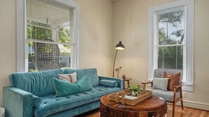 Un salon avec un canapé bleu, une table basse ronde en bois et un fauteuil gris.