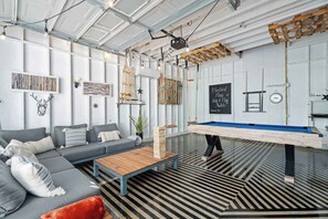 A modern lounge area with a pool table, sofas, and decorative elements.