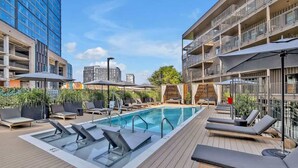 A rooftop pool with lounge chairs, umbrellas, and a view of surrounding buildings. - Hyve-Prohibition Parlor-Pool & Gym-Mins 2 Broadway (Nashville)