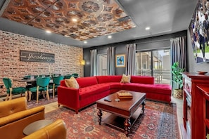Uma sala de estar moderna com um sofá seccional vermelho, uma mesa de centro de madeira e uma parede de tijolos.