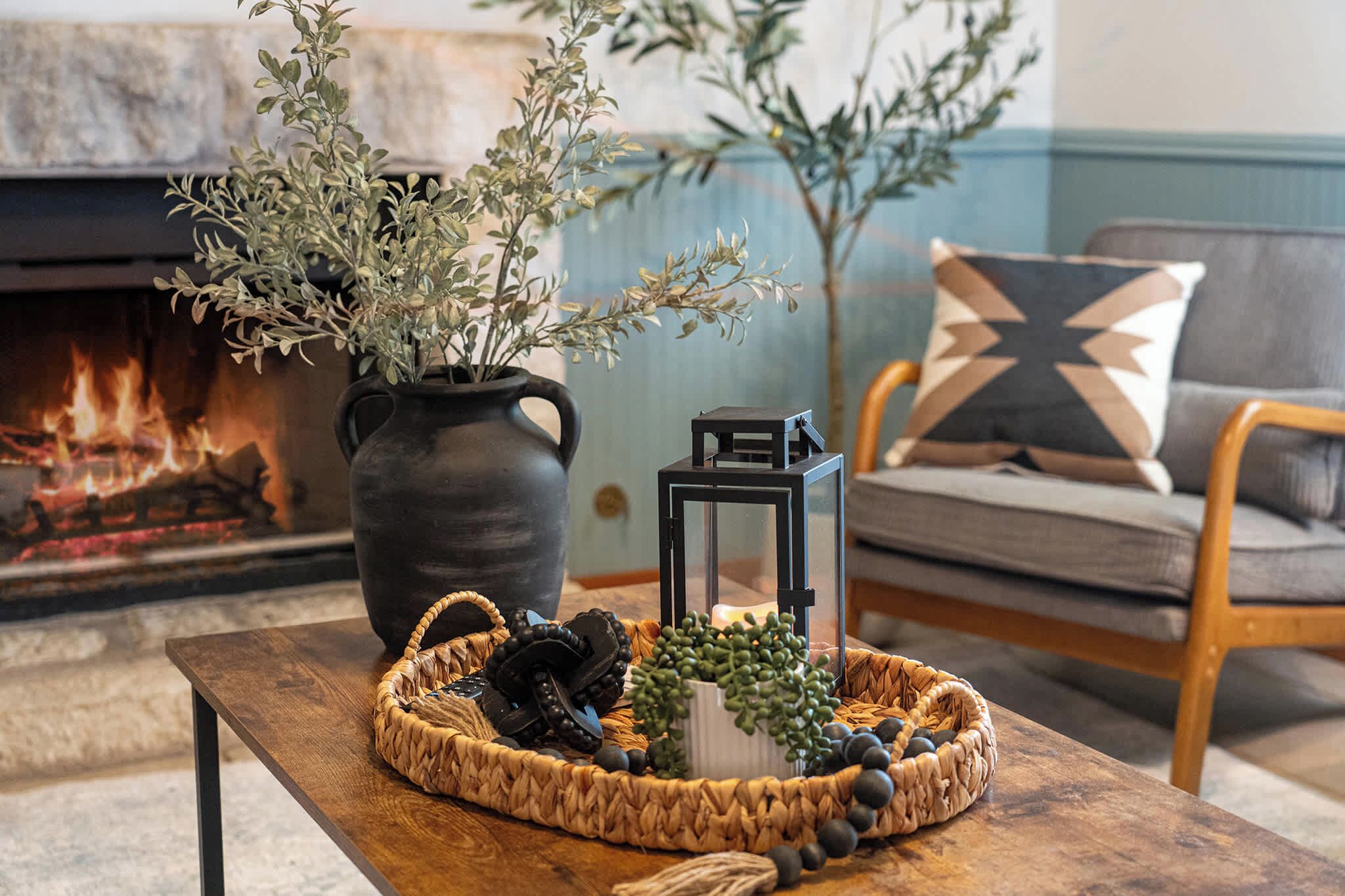 A cozy living room with a fireplace, a woven basket on a table, and a potted plant.