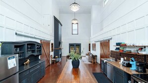 Una cocina amplia con una encimera de madera larga, una isla central con planta en maceta y vistas al comedor.