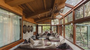Ein gemütliches Interieur mit Holzbalkendecke, großen Fenstern und einer Steinwand.