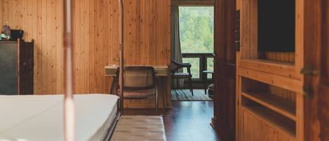 A wooden cabin interior with a bed, a desk, and a chair.