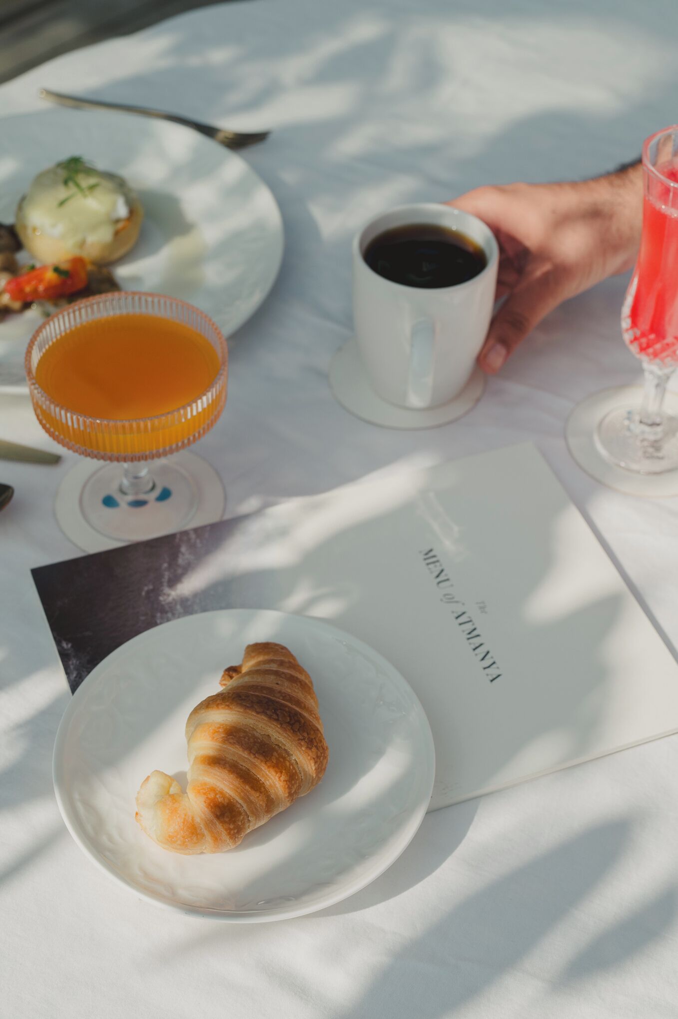 A table with a croissant, a glass of orange juice, and a cup of coffee.