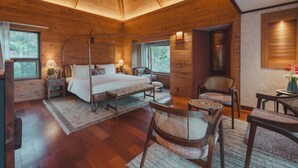 Ein Schlafzimmer einer Holzhütte mit einem Bett, Nachttischen, einem Stuhl und einem kleinen Tisch.