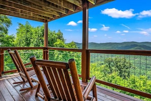Een houten terras met stoelen met uitzicht op een bergachtig landschap.