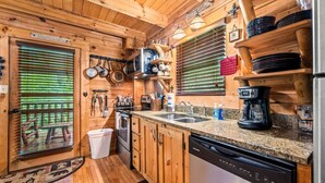 A wooden cabin kitchen with a dishwasher, stove, and sink. - 2BR Resort Cabin w/Hot Tub + Fireplace + Privacy! (Sevierville)