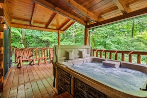 Una terraza de madera con un jacuzzi y un banco de madera.