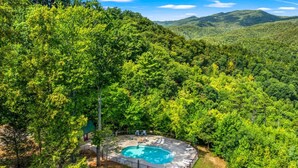 A pool surrounded by lush greenery and hills in the background. - 2BR Resort Cabin w/Hot Tub + Fireplace + Privacy! (Sevierville)