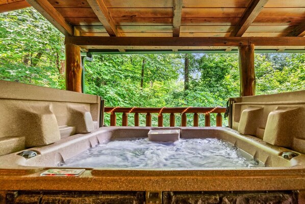 Ein Whirlpool mit einer Holzterrasse und Blick auf einen Wald.