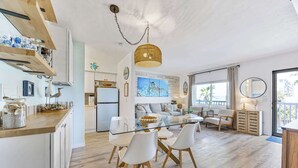 Une cuisine moderne avec une table à manger en verre, des chaises blanches et un luminaire suspendu.