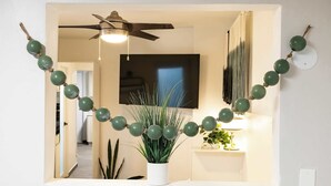 En gang med ventilator i loftet, en potteplante og et vægmonteret fjernsyn.