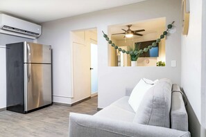 A modern kitchen with a stainless steel refrigerator, a ceiling fan, and a wall-mounted mirror.