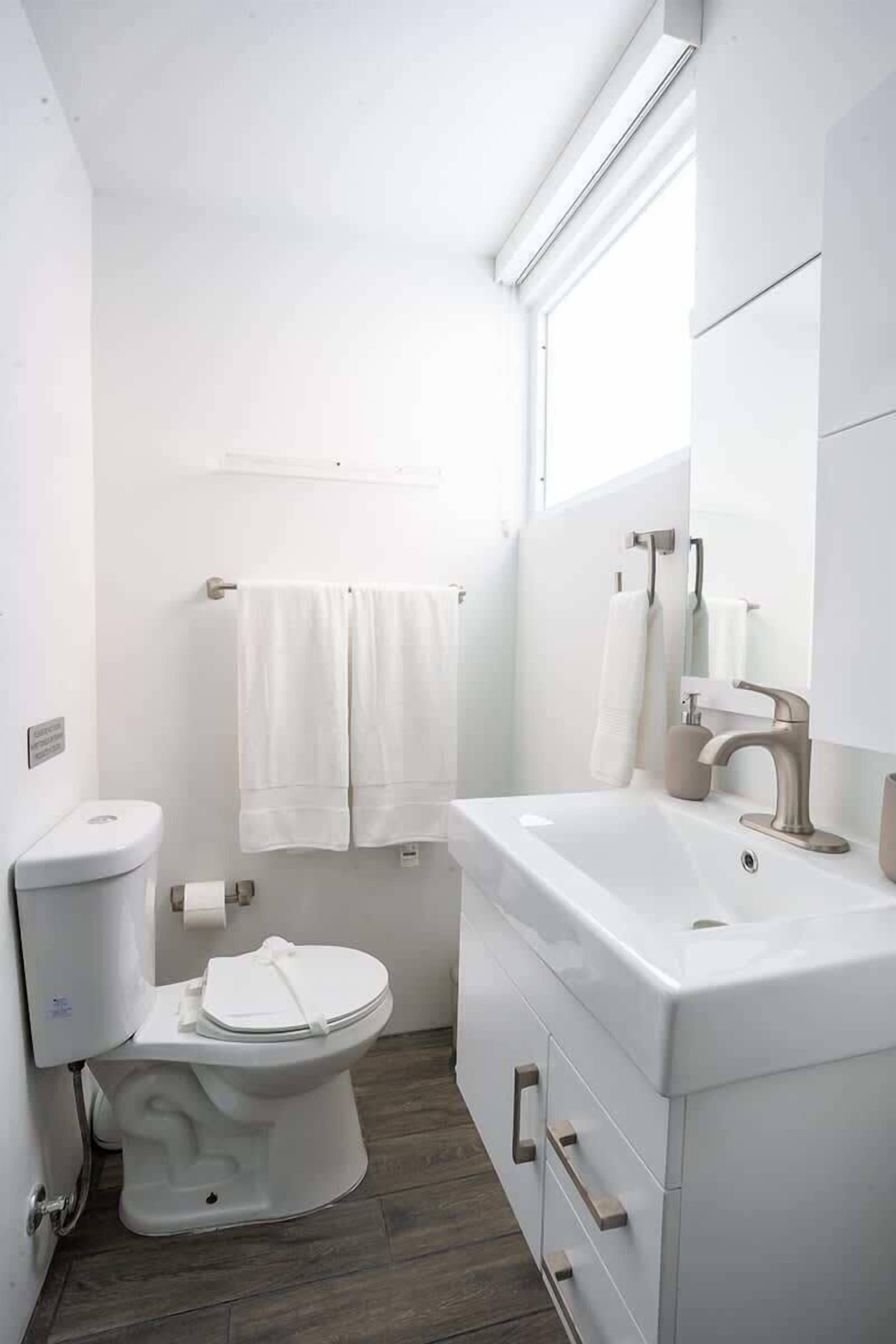 A compact bathroom with a toilet, sink, and mirror.