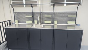 A kitchenette with a stainless steel sink, two cabinets, and a window with blinds. - AQUA Terrazas # 5 Plus a included Celebration or event Rooftop up to additional  30 visitors Oceanfront, Pool & Local Dining (Dorado)