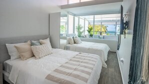 Een moderne slaapkamer met twee bedden, grote ramen en uitzicht op de omgeving.
