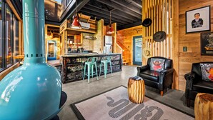 Un interior moderno con zona de bar, detalles de madera y un gran jarro turquesa.