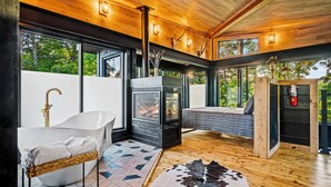 Un baño moderno con una bañera independiente, una estufa de leña y un ventanal grande.