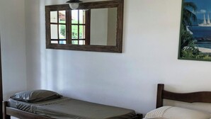 Een slaapkamer met twee eenpersoonsbedden, een raam met uitzicht, een spiegel en een schilderij aan de muur.