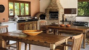 Een landelijke keuken met een bakoven, houten meubels en uitzicht op groen.