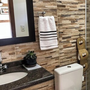 A bathroom with a granite countertop, a sink, a toilet, and a towel rack with a white towel.