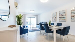 A modern dining area with a white table, blue chairs, and a large window with a view.