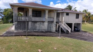 A two-story house with a balcony, a covered porch, and a carport. - Beautiful 2-bed House in St George (Workmans)