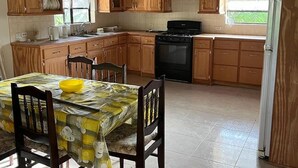 A kitchen with wooden cabinets, a stove, and a dining table with chairs. - Beautiful 2-bed House in St George (Workmans)