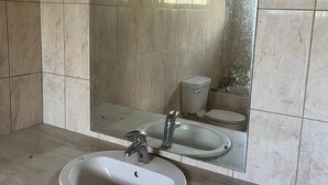 A bathroom with a large mirror, two sinks, and a toilet. - Beautiful 2-bed House in St George (Workmans)
