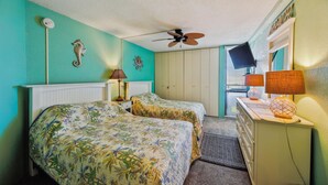 A room with two beds, a ceiling fan, a desk with a lamp, and a window with blinds. - Includes Xplorie Activities & Linens. PYRAMID-1BR OF condo w/outdoor pool. (Ocean City)