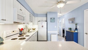 A kitchen with white cabinets, a white refrigerator, a microwave, a stove, and a ceiling fan. - Xplorie Activities and Linens Included. Great 2BR/2BA bayfront condo on 94th Street! (Ocean City)