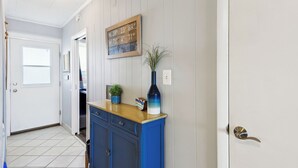 A hallway with a wooden sign, a blue cabinet, a potted plant, and a door with a brass handle. - Xplorie Activities and Linens Included. Great 2BR/2BA bayfront condo on 94th Street! (Ocean City)