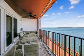 Een balkon met uitzicht op zee, een plafondventilator en tuinmeubilair.