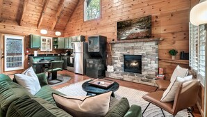 Interior acogedor de una cabaña con chimenea de piedra, techo de madera y una zona de comedor.