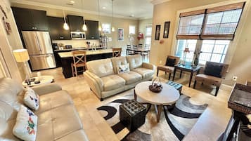 Un salón amplio con un sofá color beige, una mesa de centro y una zona de comedor con una mesa y sillas.