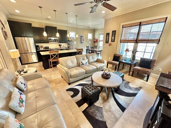 A spacious living room with a beige sofa, a coffee table, and a dining area with a table and chairs.