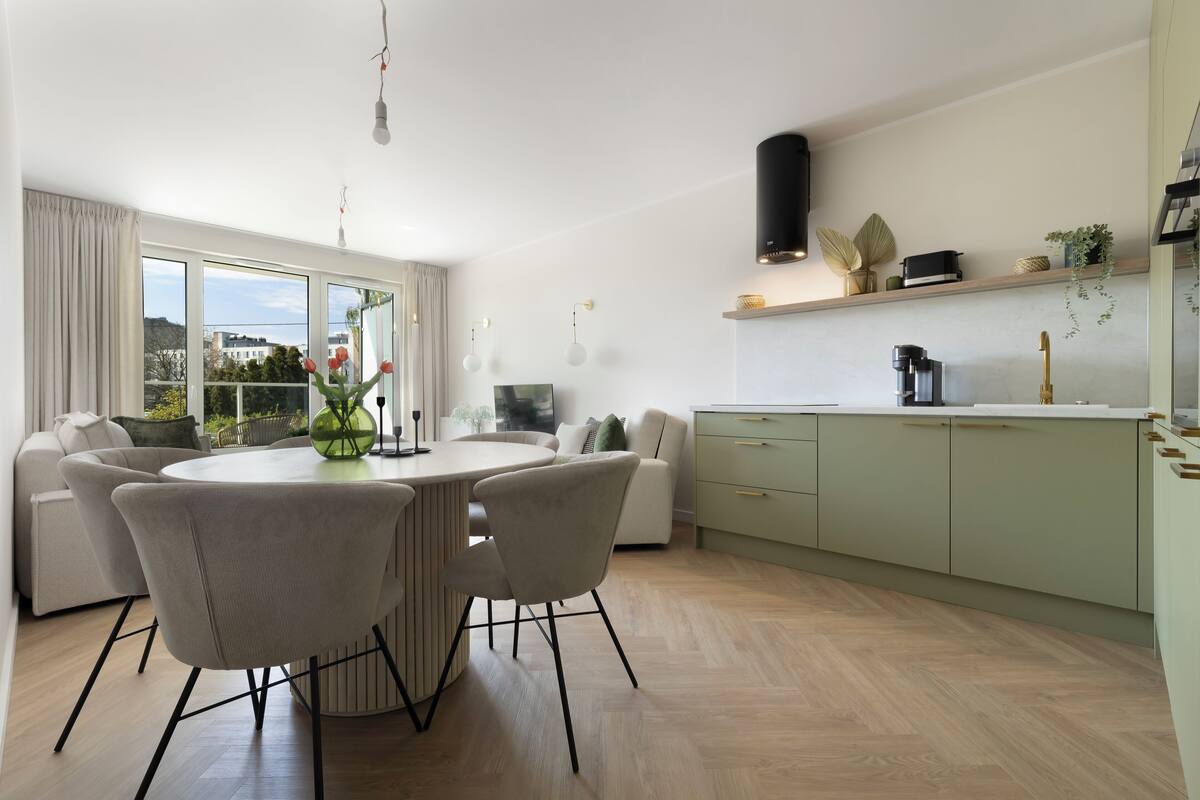 A modern kitchen with a dining area, large windows, and a view of the outdoors.