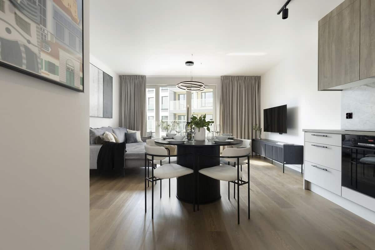 A modern kitchen with a dining area, a sofa, and a TV.