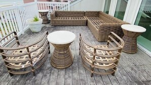 A balcony with wicker furniture, including chairs and a sofa, and a potted plant.