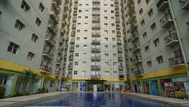 A high-rise residential building with a swimming pool in the center. - Hotel O Metro Suite Apartment By Pian (Bandung)