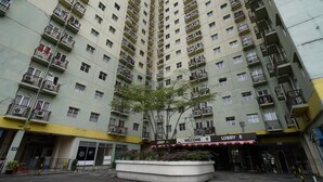 A high-rise building with multiple balconies and a central courtyard with a tree. - Hotel O Metro Suite Apartment By Pian (Bandung)