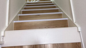 Un escalier en bois, avec des murs blancs et une rampe blanche.
