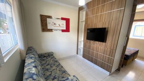 A living room with a sofa, a mounted TV, and a wooden accent wall. - Lacqua diRoma - Caldas Novas (Caldas Novas)
