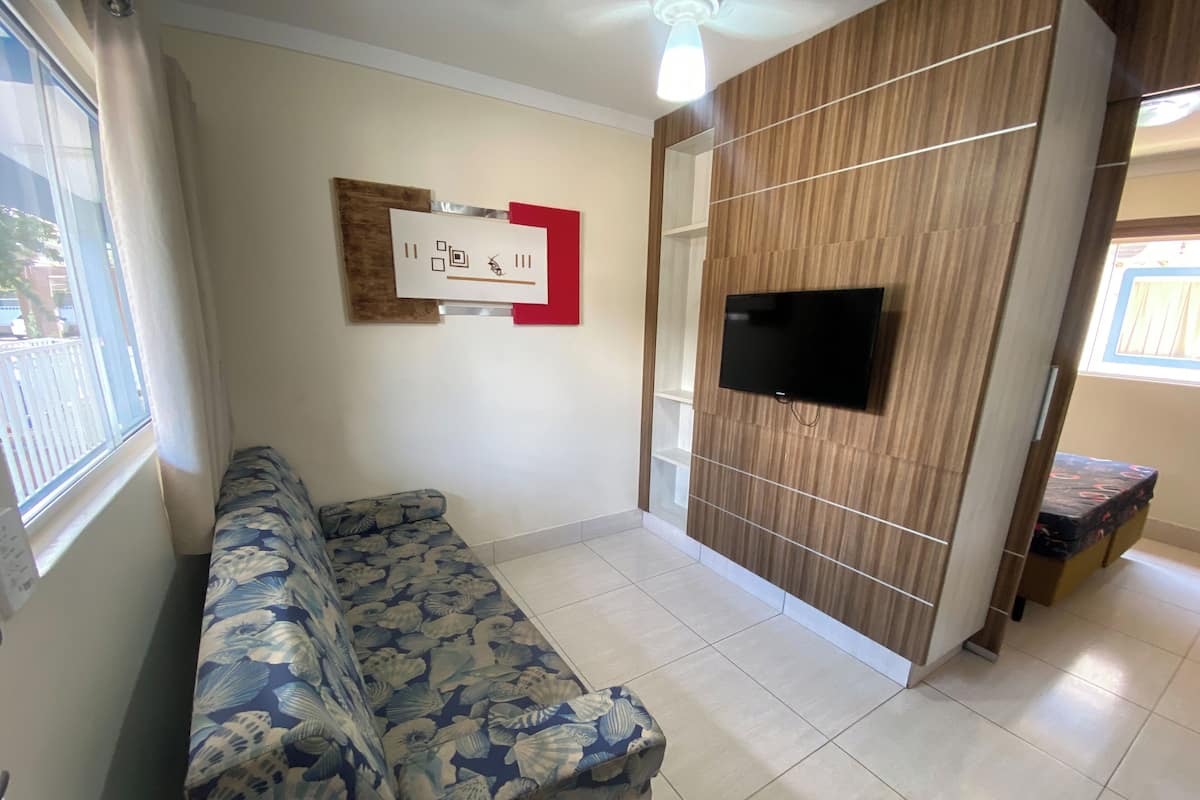 Un salon avec un canapé, un téléviseur fixé au mur et un mur d’accent en bois.