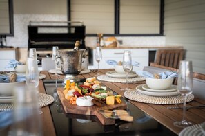 A dining table set with a variety of cheeses, charcuterie, and a bottle of champagne. - Airlie Nights (Airlie Beach)