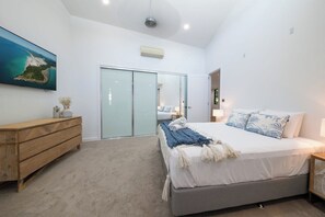 Un dormitorio con una cama, un aparador de madera, una puerta corrediza de cristal y un cuadro en la pared.